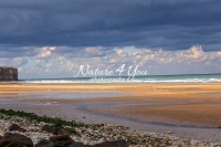 Fast surf at the beach splashing on chalk cliffs with upcoming storm